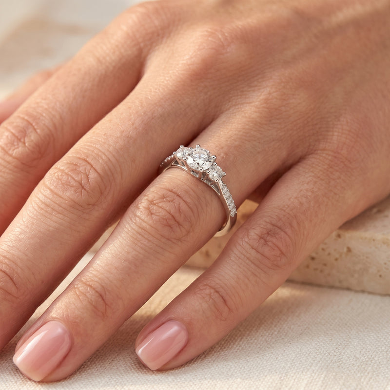 Round cut simulated diamond Roselysse promise ring in sterling silver worn on a woman's finger.