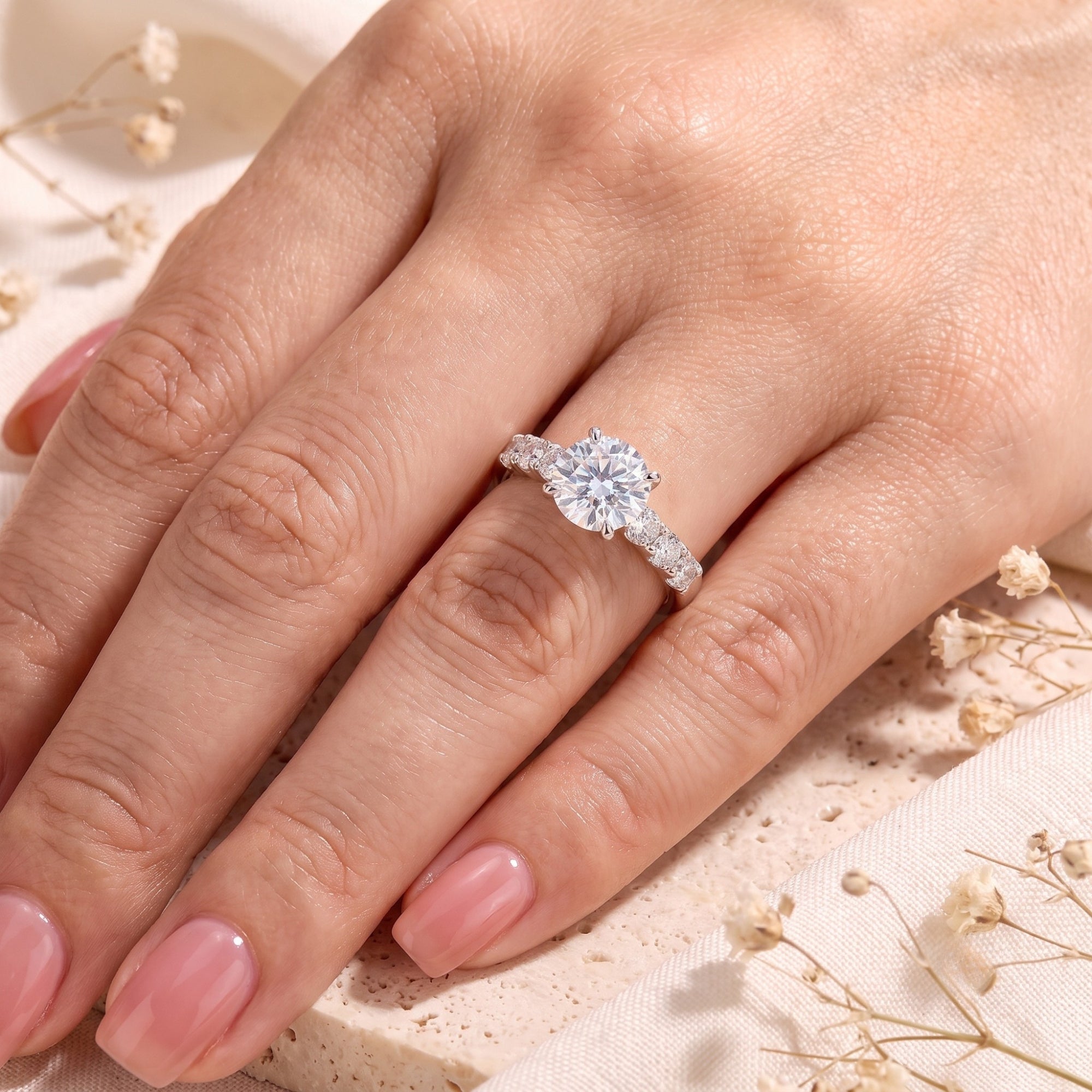 Round simulated diamond solitaire ring in sterling silver worn on a woman's ring finger.