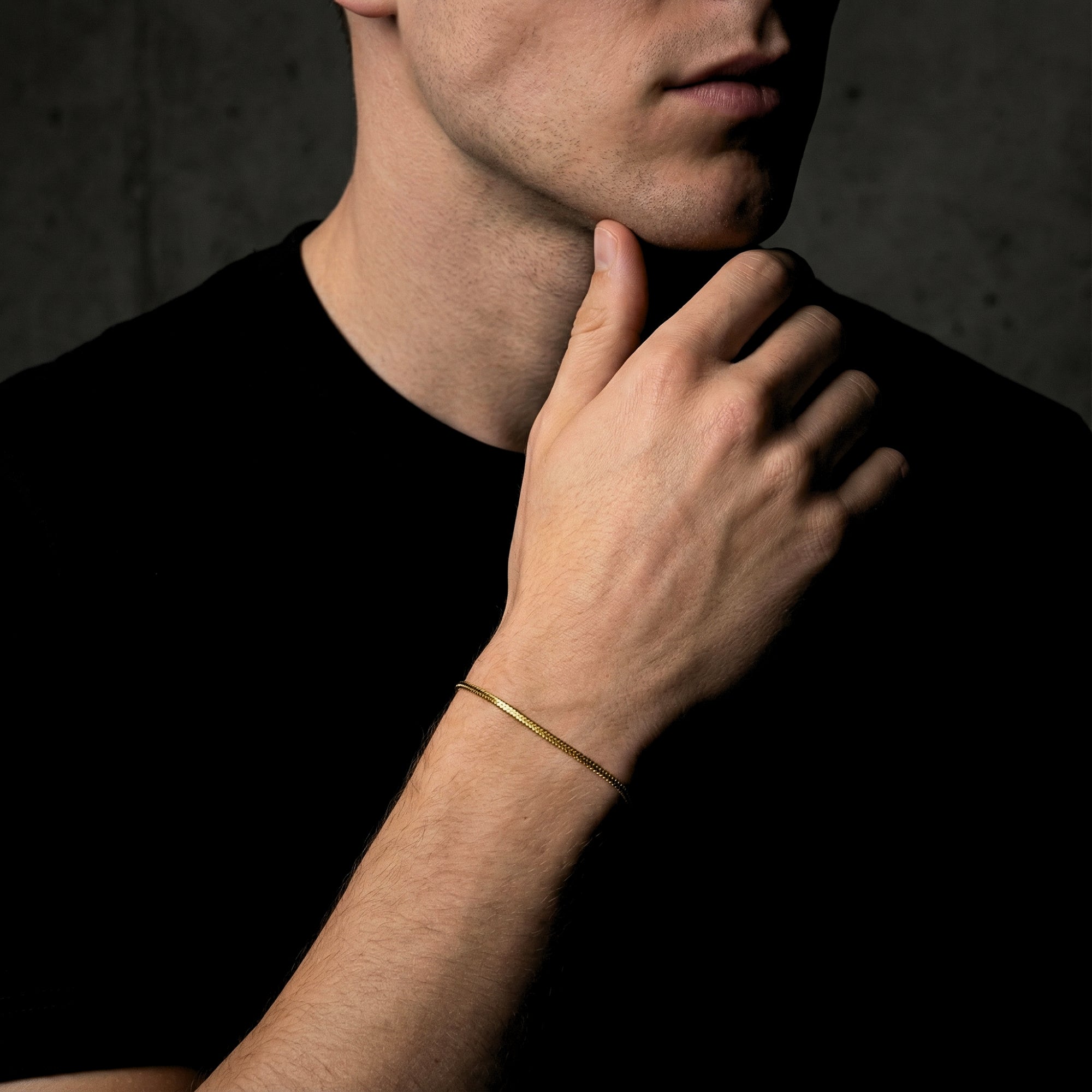 Men's gold-tone stainless steel square link bracelet styled on a wrist with a black t-shirt.