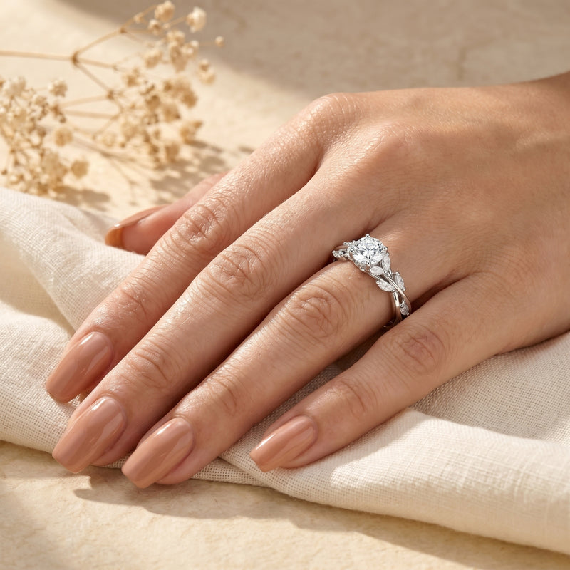 Calyxta moissanite ring with round center stone and marquise accents worn on a woman's hand.