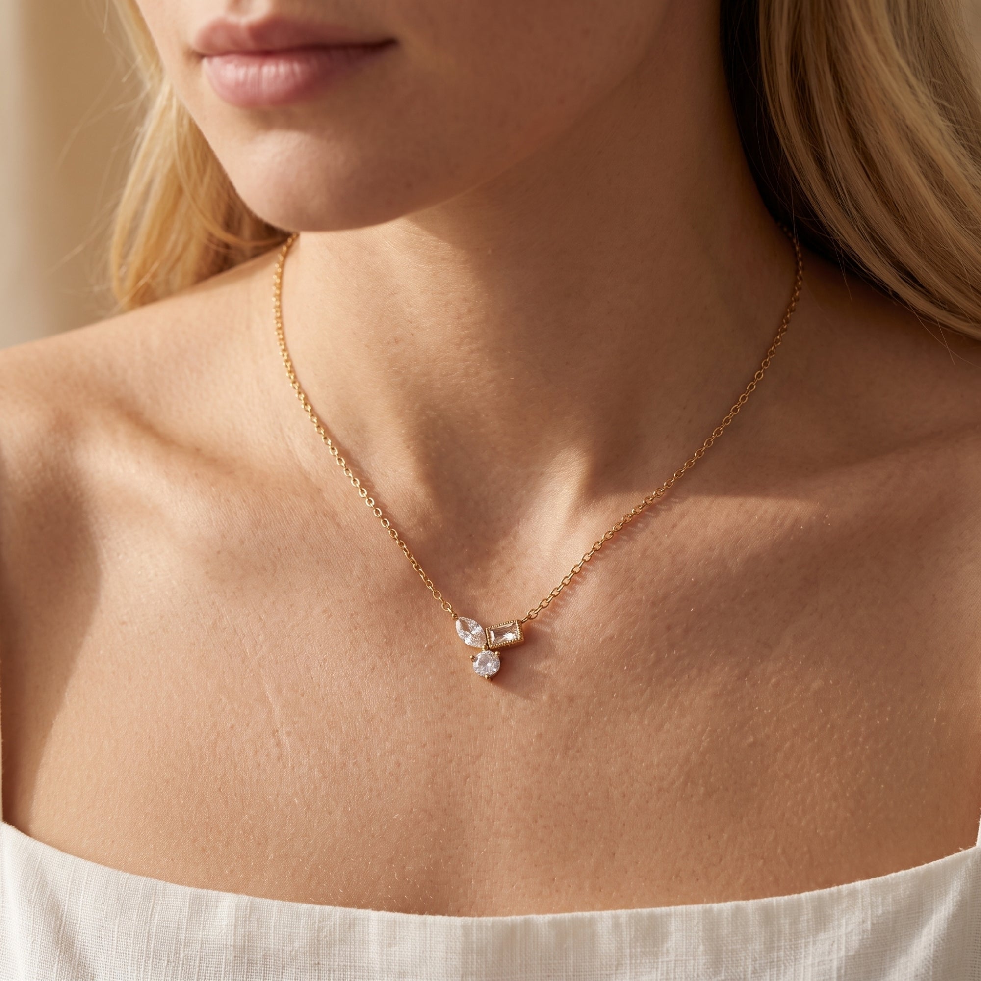 Woman wearing the 18K gold Elyssara necklace with a geometric cubic zirconia cluster pendant.