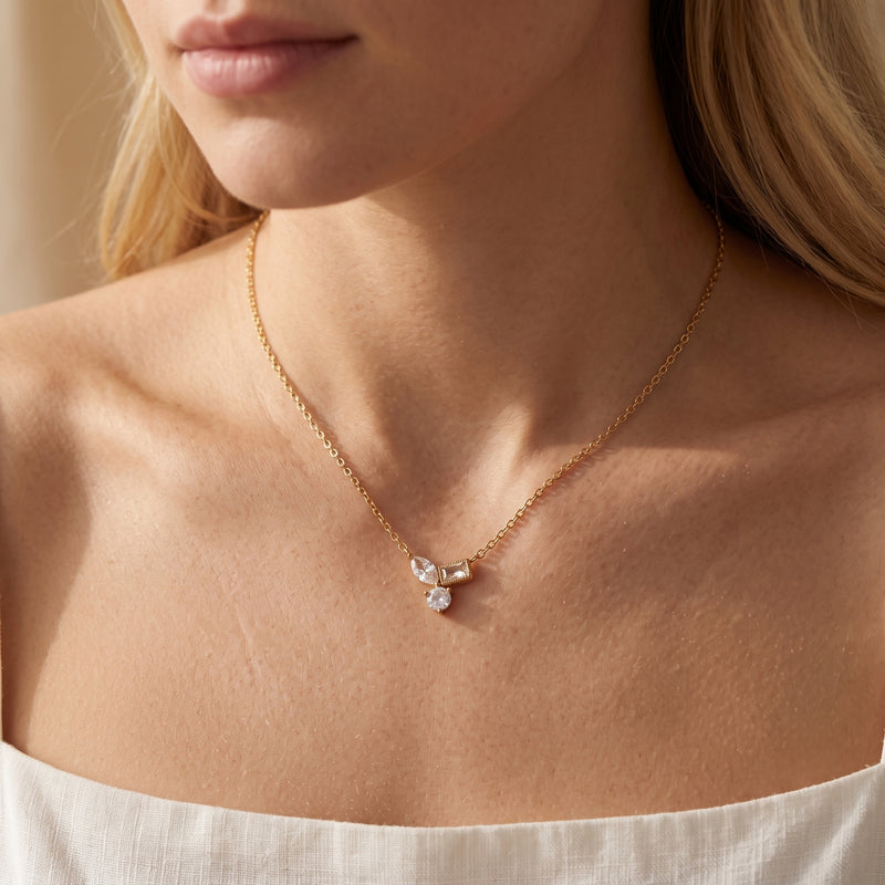 Woman wearing the 18K gold Elyssara necklace with a geometric cubic zirconia cluster pendant.