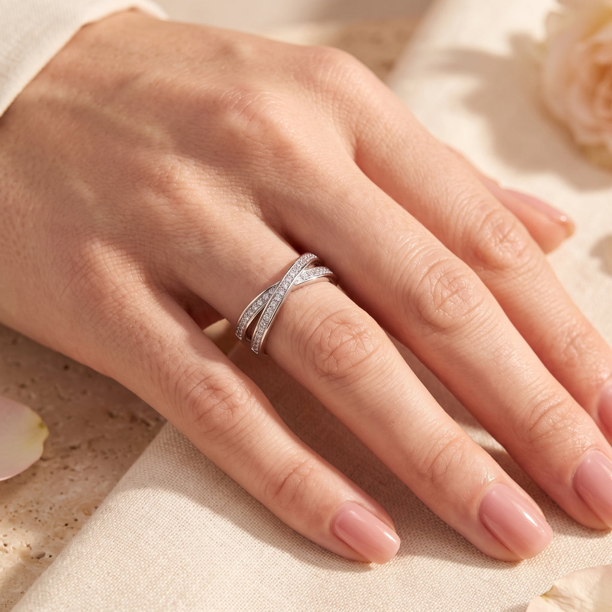 Sterling silver Nerise crossover ring with cubic zirconia worn on a woman's finger.