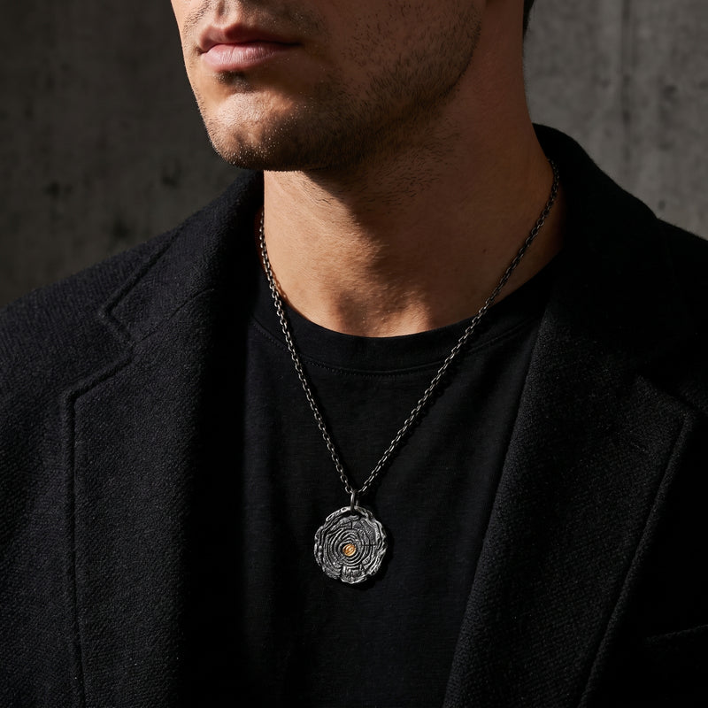 Man wearing the growth ring pendant necklace with a black T-shirt and dark blazer.