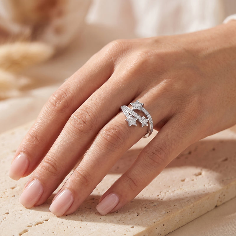Silver shooting star bypass ring with three pave-set stars worn on a ring finger.