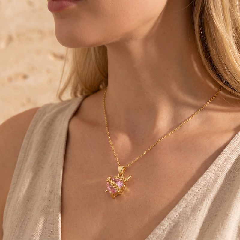 Side angle of a model wearing the gold-tone necklace with a pink heart crystal pendant.