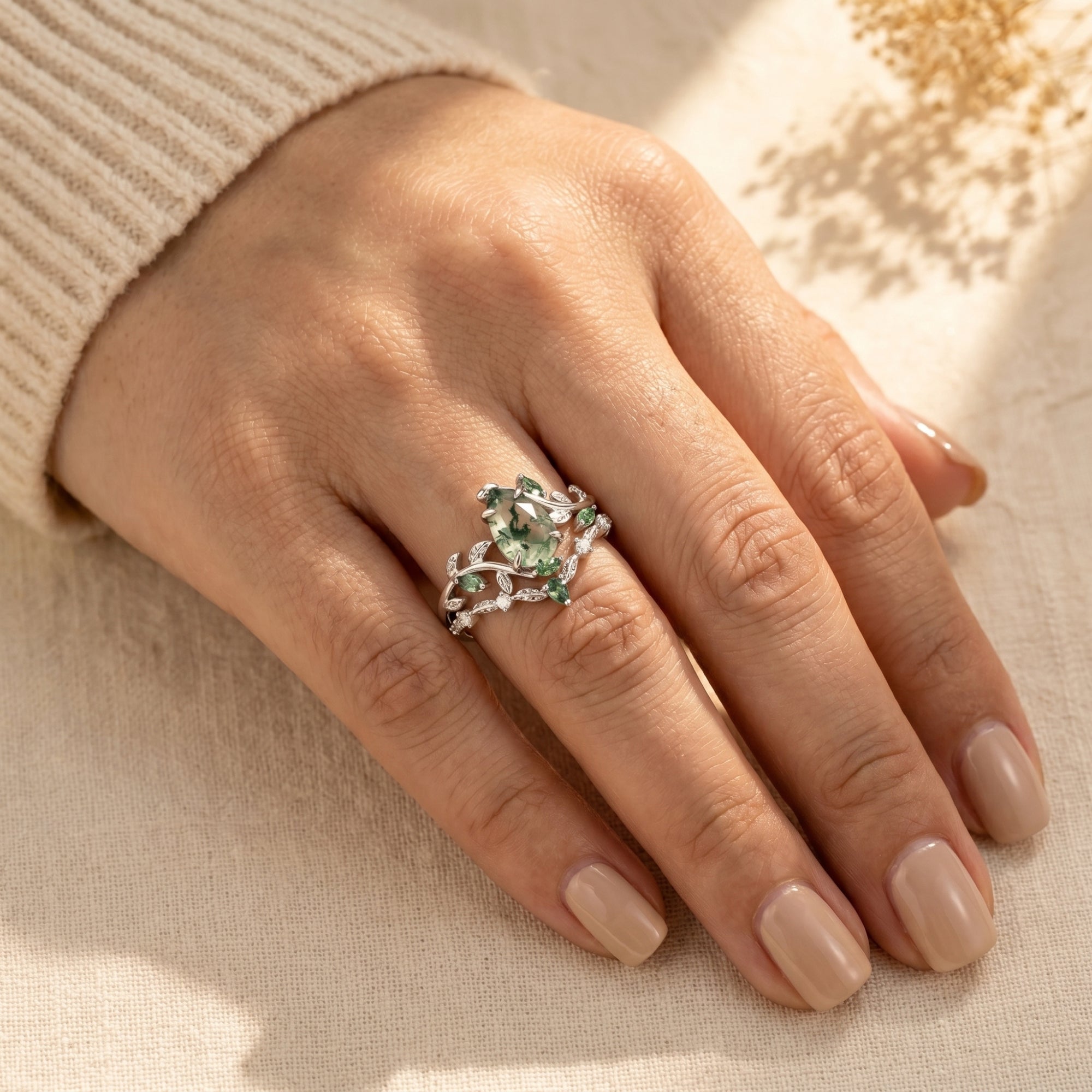 Woman wearing the silver Cypria moss agate vine ring set with a pear-cut center stone on her finger.