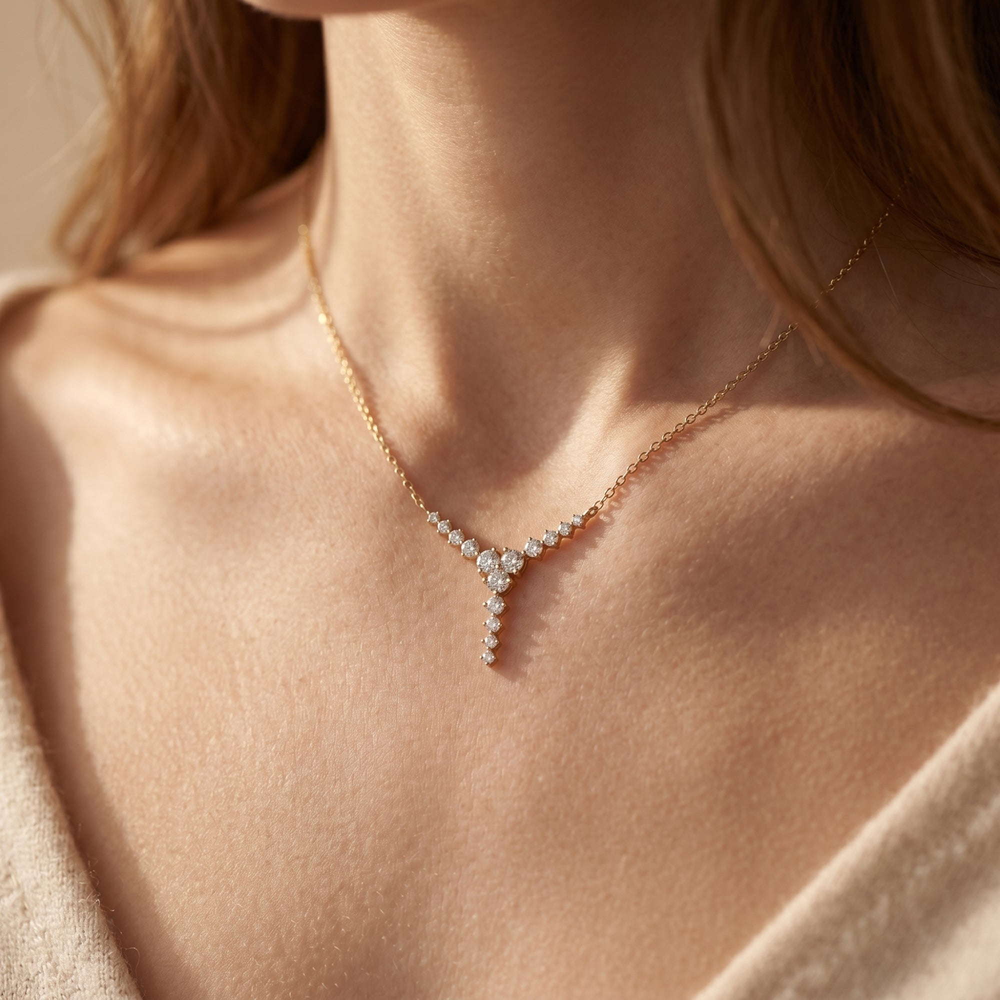 Gold moissanite cascading drop necklace worn on a woman's neck.