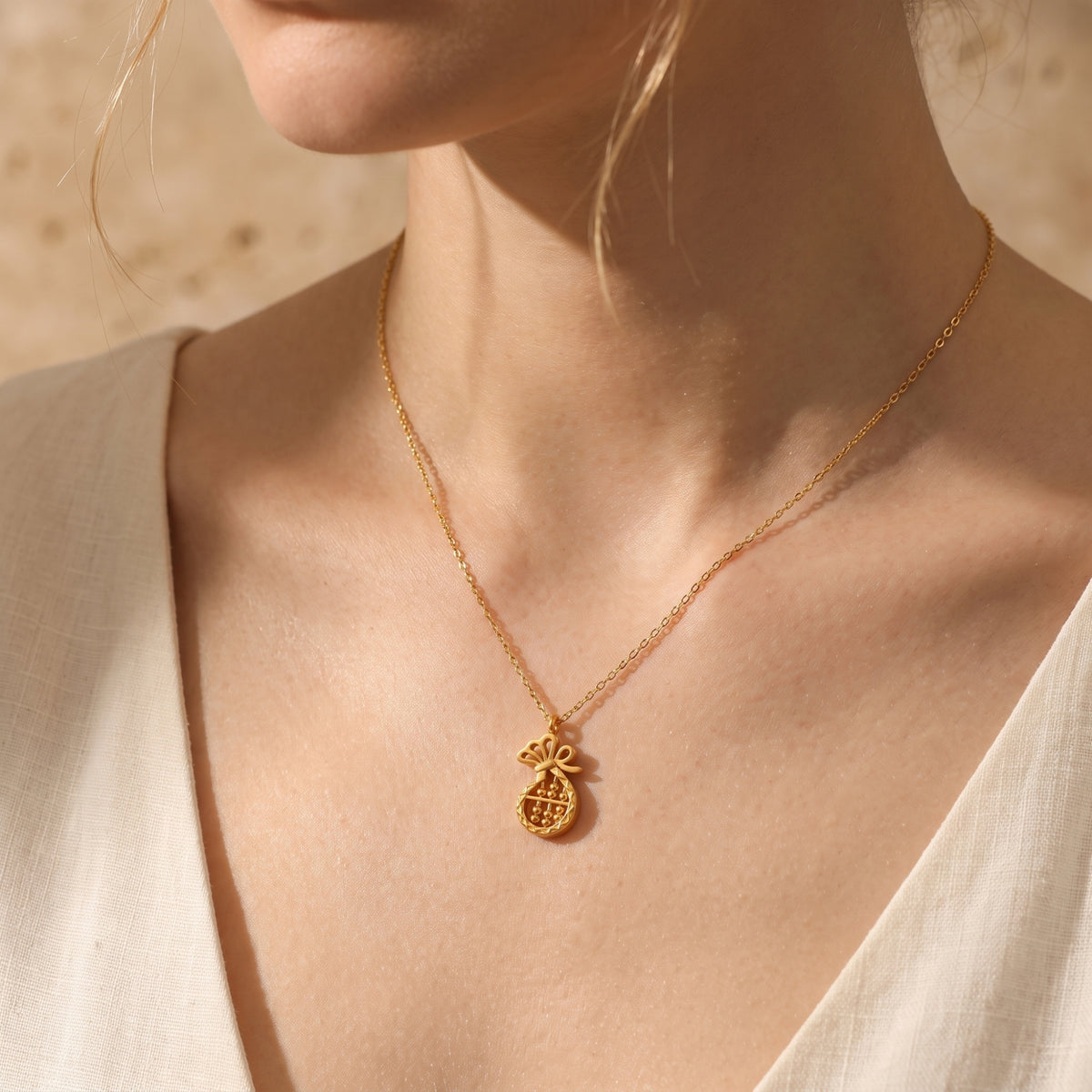 Model wearing the gold-tone fortune abacus necklace with a white V-neck top.