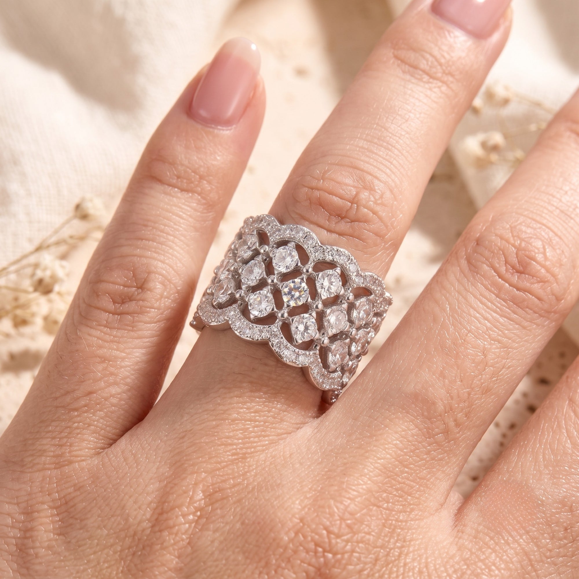 Carisienne silver filigree ring with simulated diamonds worn on a finger.