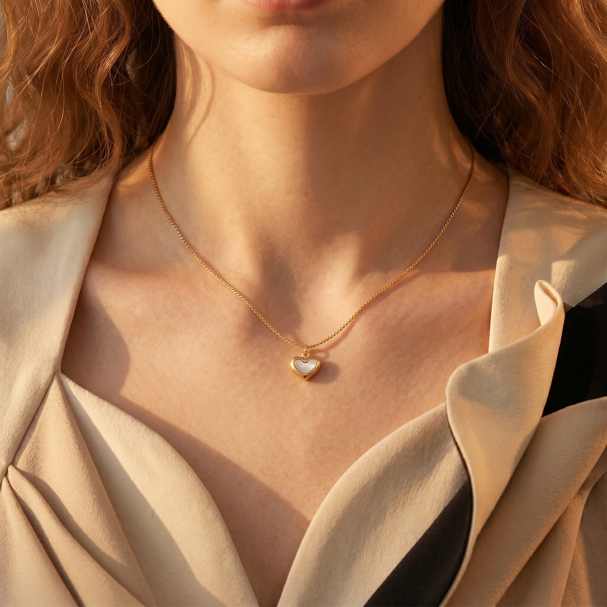 Gold heart pendant necklace with white inlay worn by a model against a neutral top.