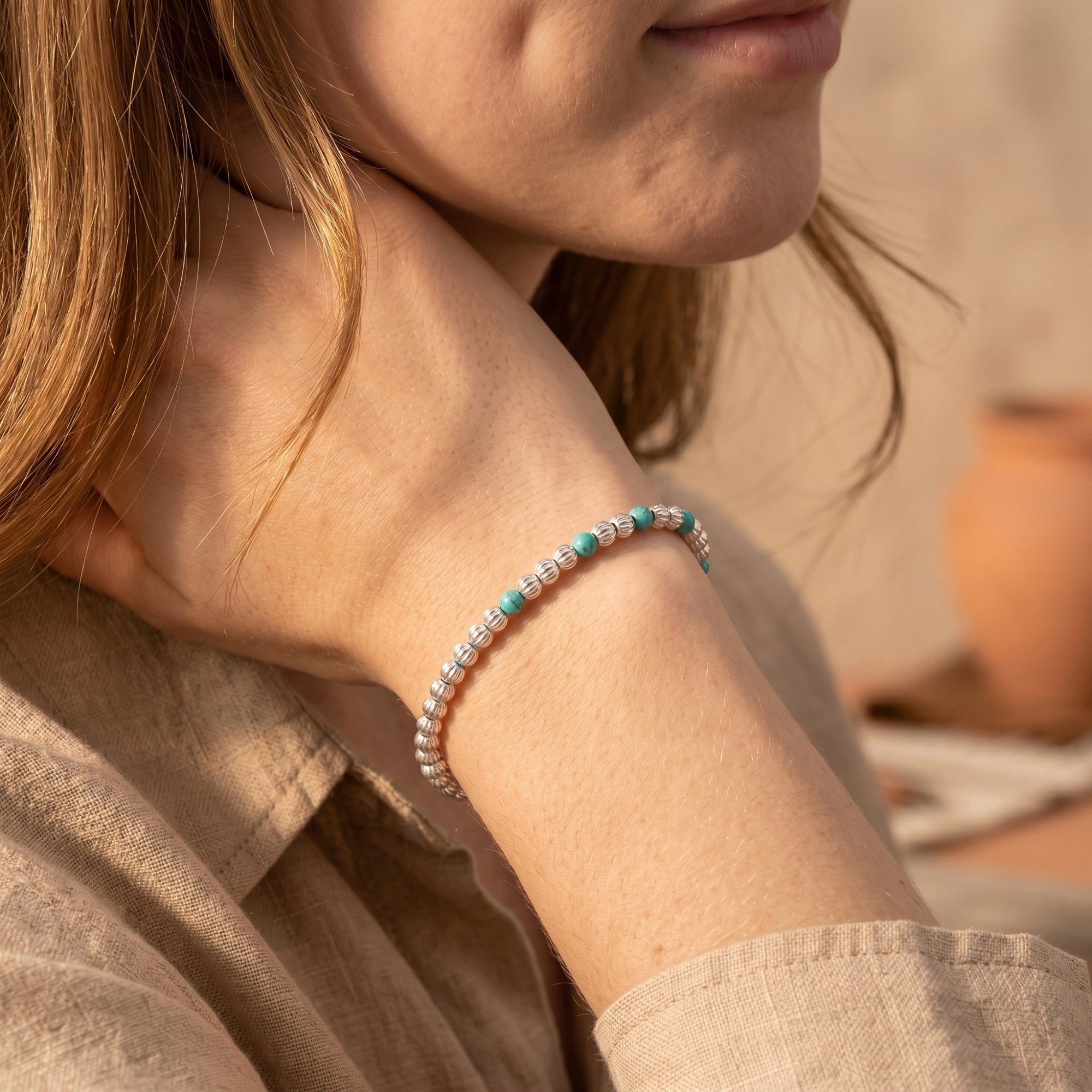 Silver bead bracelet with turquoise accents worn on a wrist.