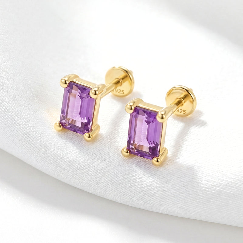 Angled view of 18K gold vermeil emerald cut amethyst studs showing the four-prong setting on white fabric.