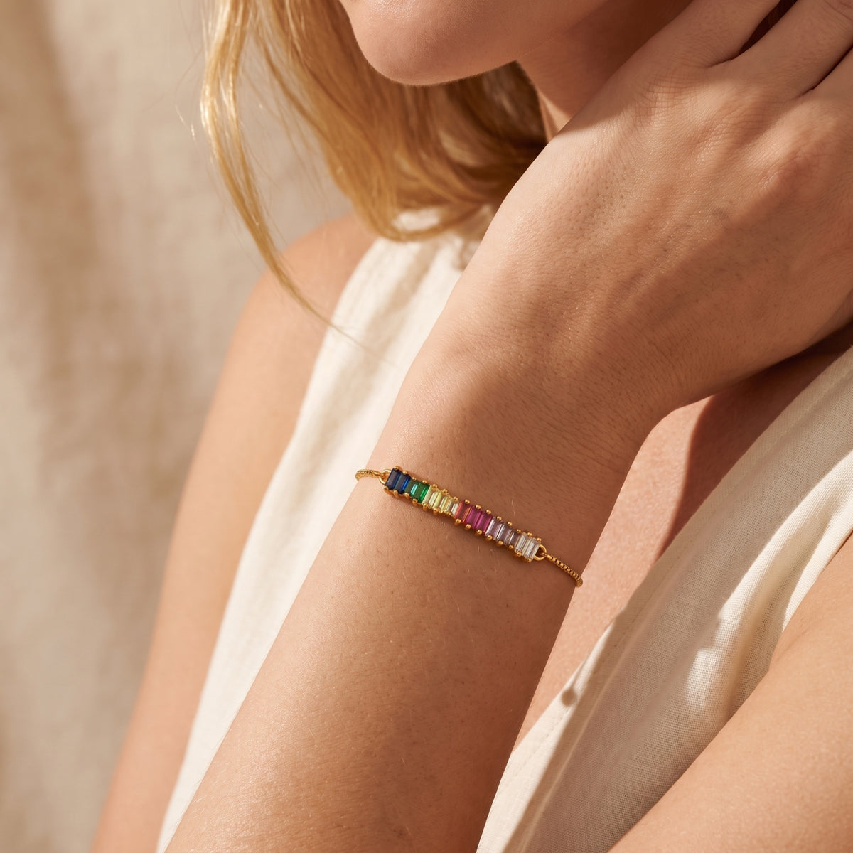 Model wearing the gold-tone rainbow baguette slider bracelet around her wrist.
