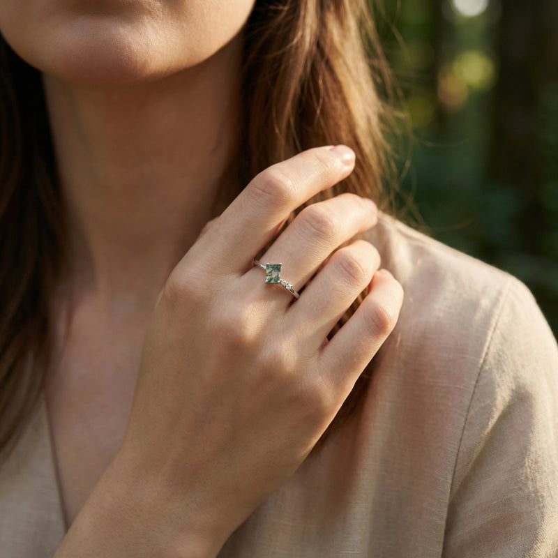 Natural moss agate S925 sterling silver ring worn on a woman's hand in a soft outdoor forest setting.