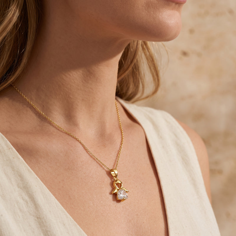 Side profile of a woman wearing the gold-tone angel pendant necklace with a white sleeveless top.