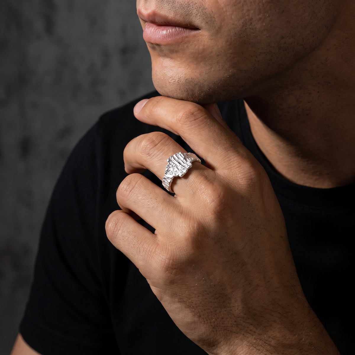 Close-up of a man wearing the textured silver bark ring on his ring finger while resting his chin.