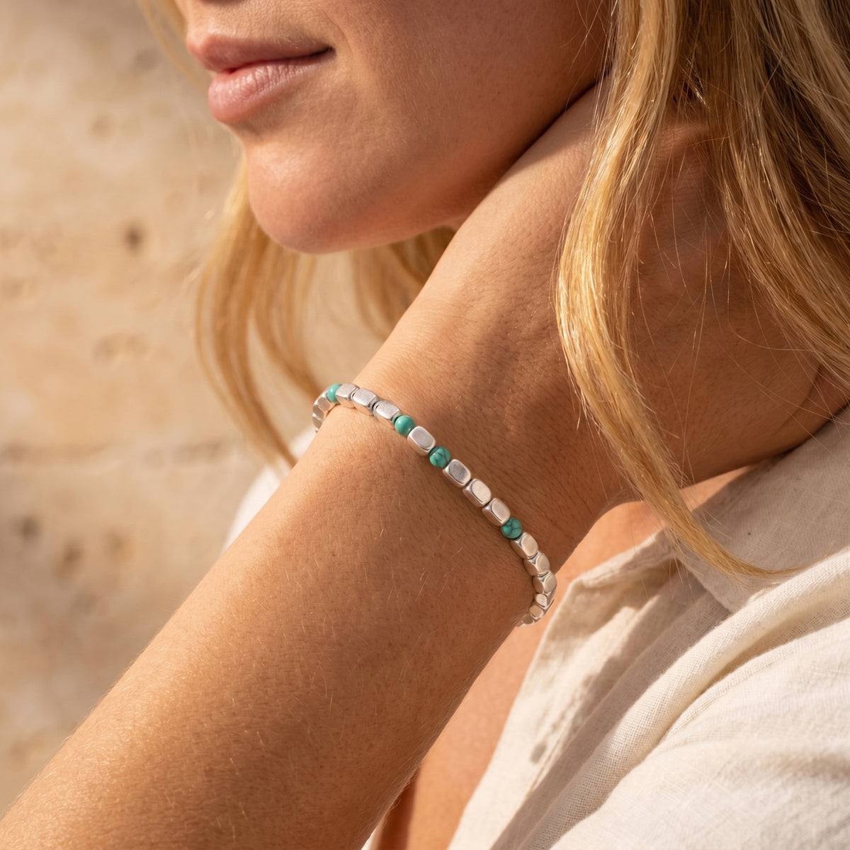 Navajo-style silver and turquoise bead bracelet worn on a woman's wrist.