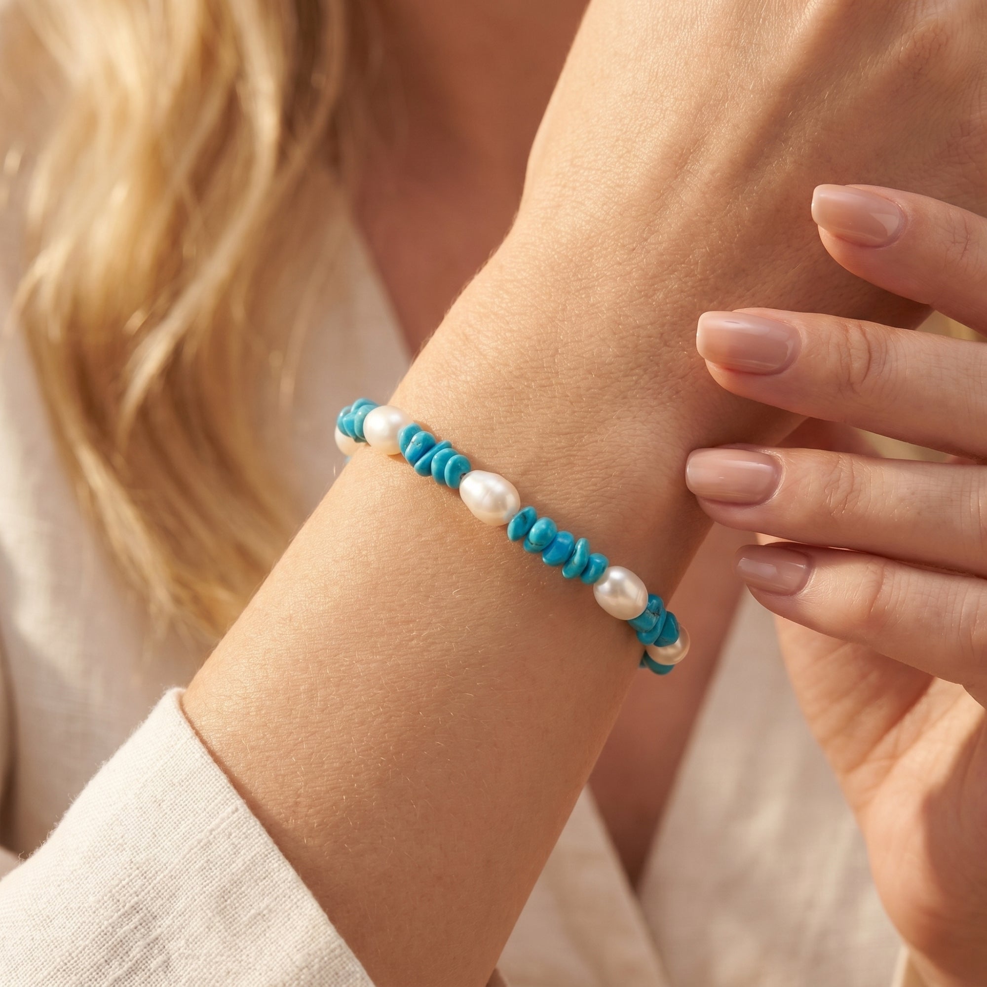 Close-up of the turquoise and white pearl silver bracelet worn on a woman's wrist.