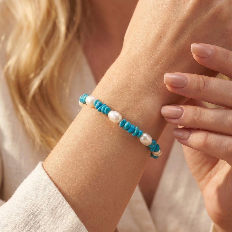 Close-up of the turquoise and white pearl silver bracelet worn on a woman's wrist.
