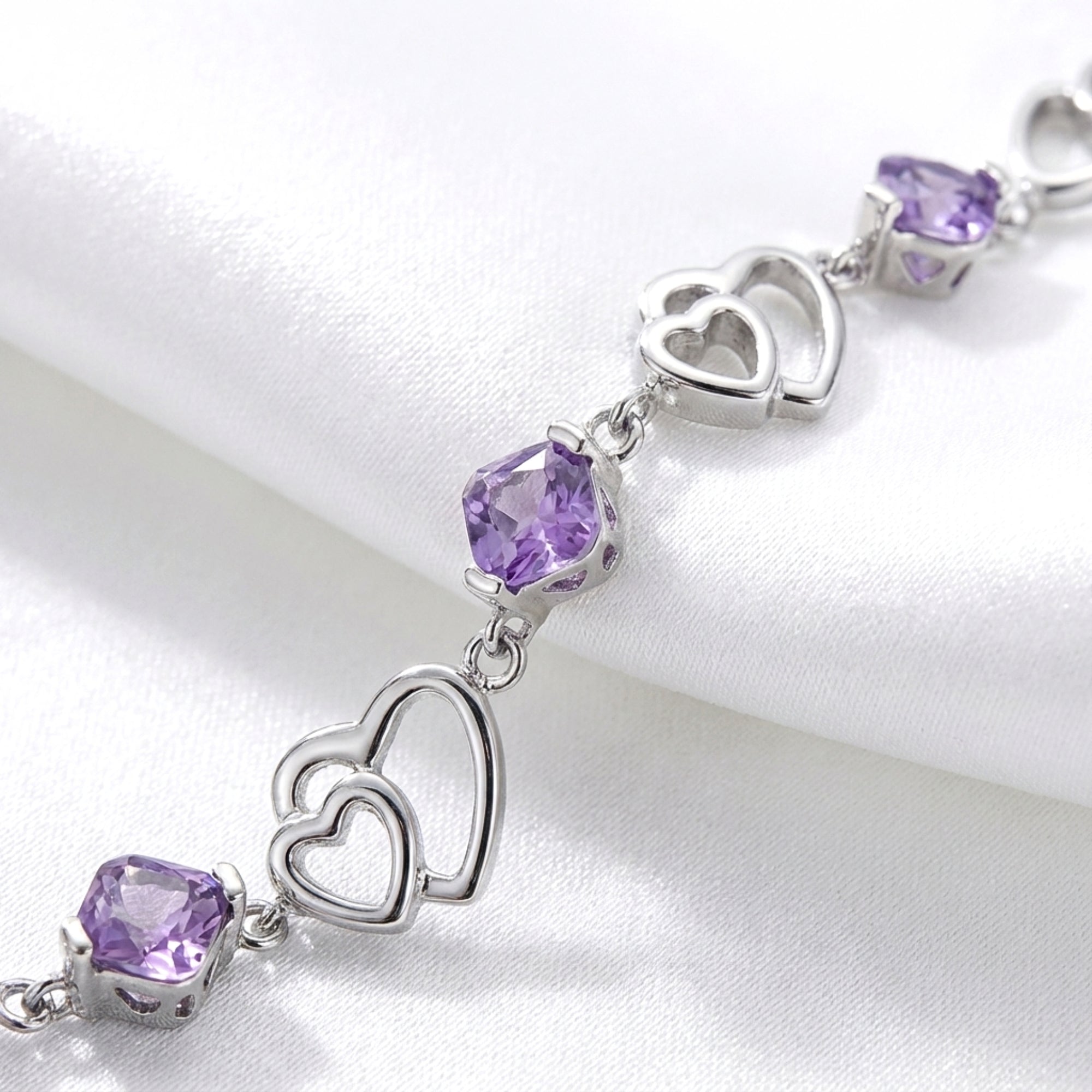 Macro detail of the sterling silver heart links and faceted purple simulated amethyst stones.