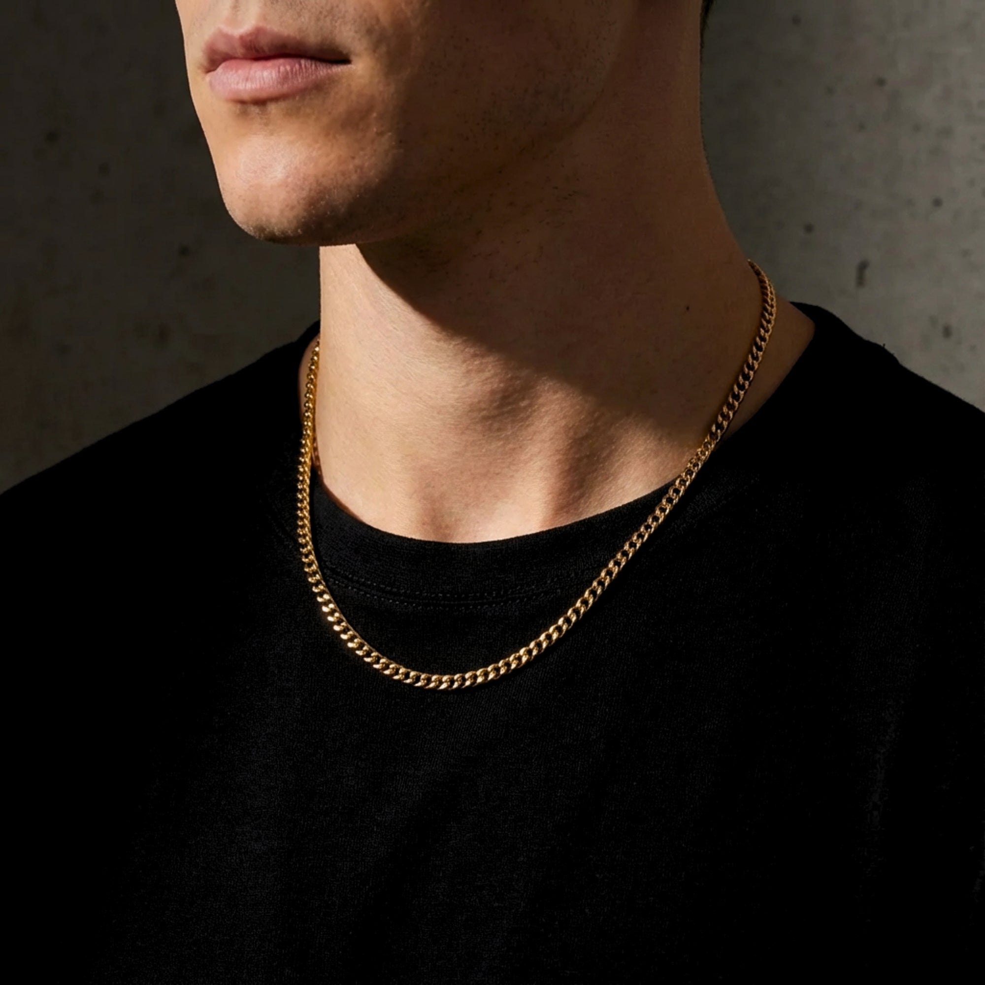Man wearing a 4mm gold stainless steel Cuban chain necklace over a black t-shirt.