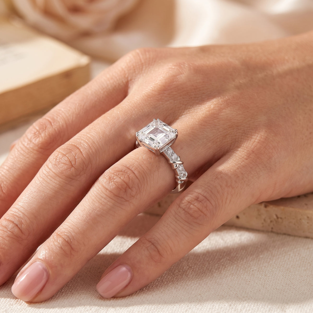 Angled view of the silver ring worn on a hand, showing the raised emerald-cut center stone and twisted accent band.