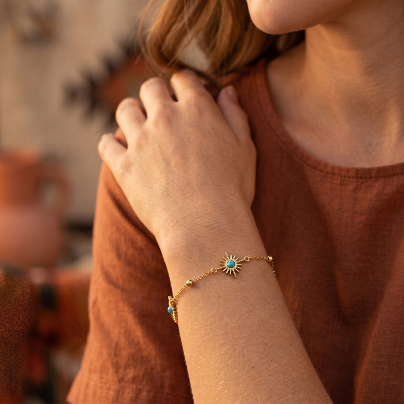 Woman wearing the 18K gold finish Santa Ana turquoise sunburst chain bracelet on her wrist.