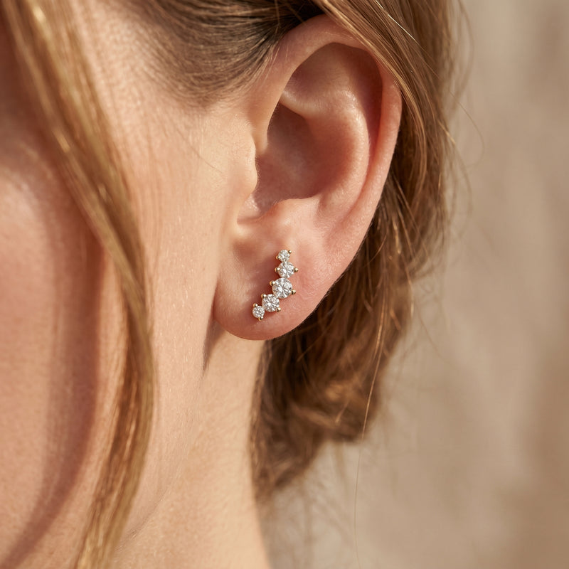 Gold moissanite crawler earring worn on ear showing curved five-stone design.