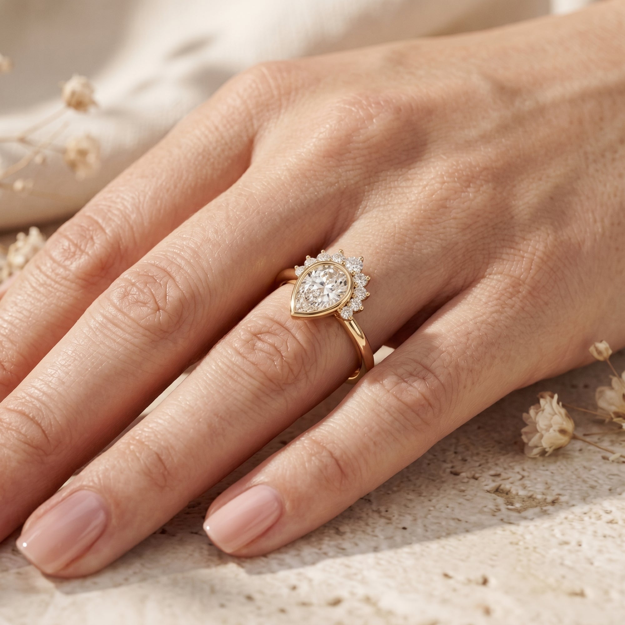 Gold pear-cut moissanite ring with crown accents worn on a woman's finger.