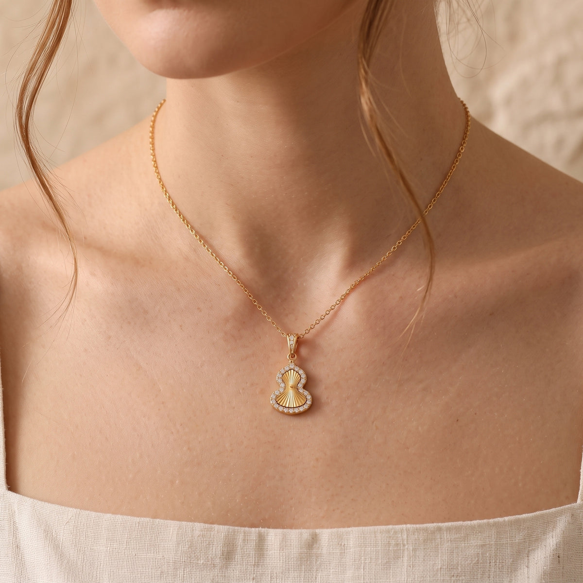 Gold PVD stainless steel Sorsha necklace with gourd pendant worn by a model.