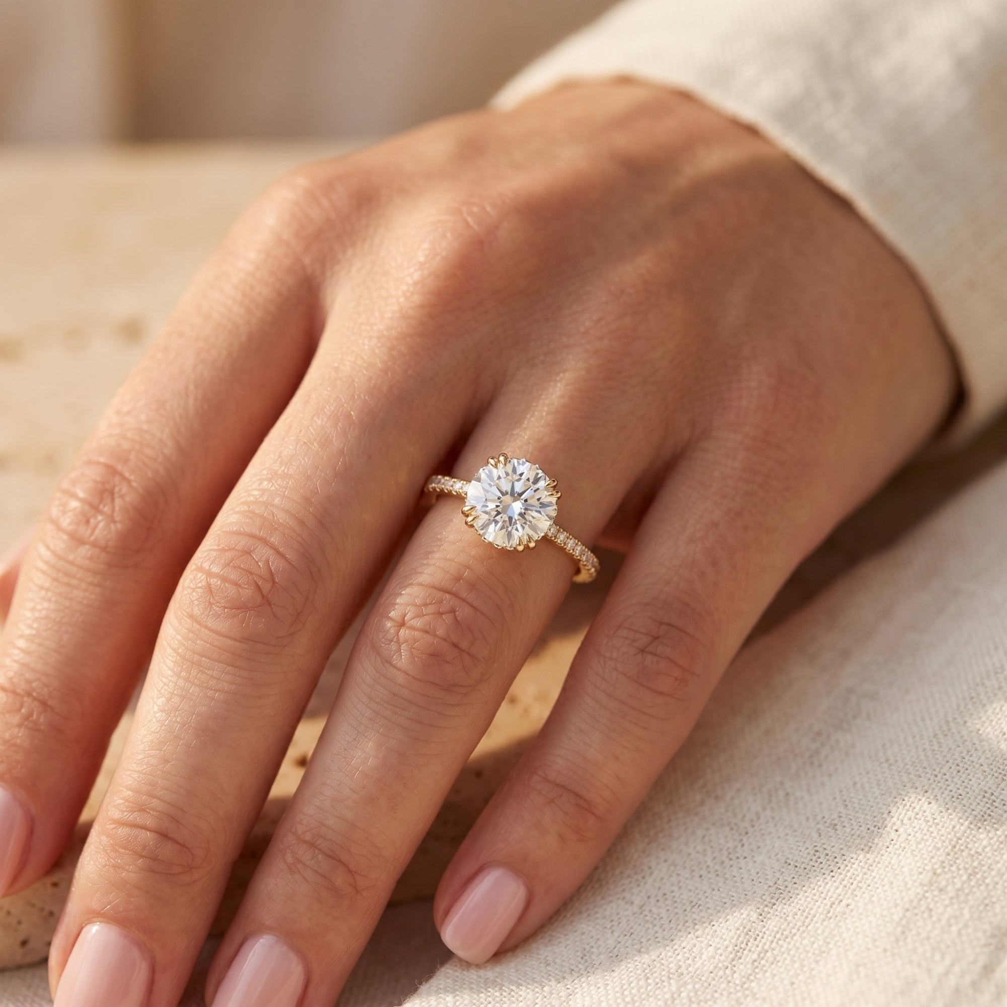 2-carat round moissanite solitaire ring in gold worn on a woman's hand.