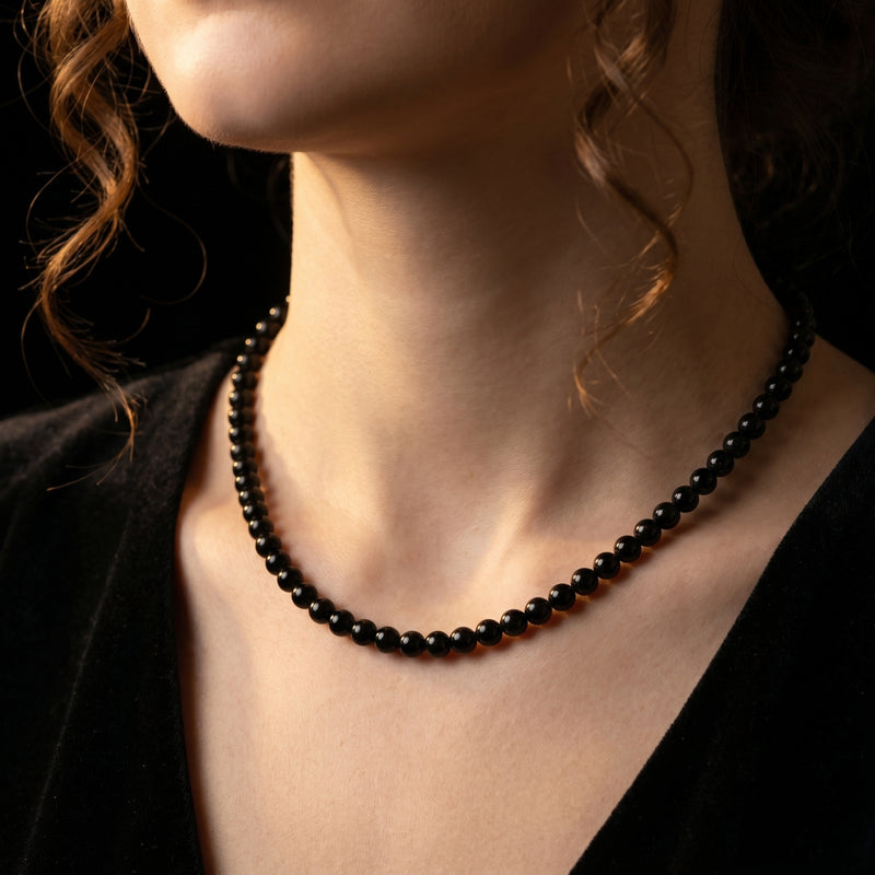 Close-up of a model wearing the 6mm round black onyx beaded necklace against a dark background.