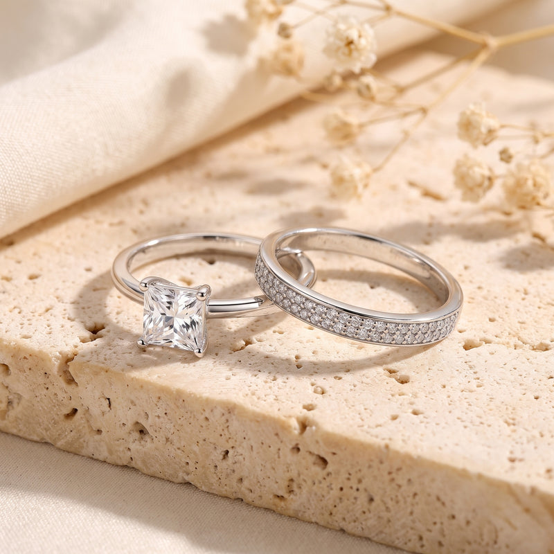 Side view of sterling silver princess cut solitaire and pavé band on a stone surface.