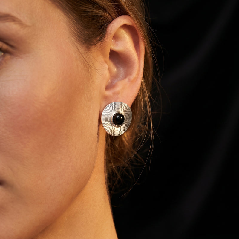 Woman wearing a silver Architect stud earring with a round black onyx cabochon on her ear.