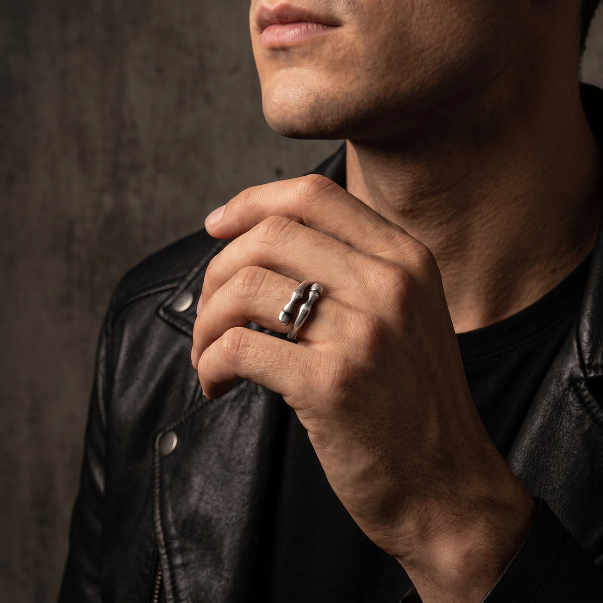 Model wearing a sculpted 999 fine silver open-band ring with a black leather jacket visible.