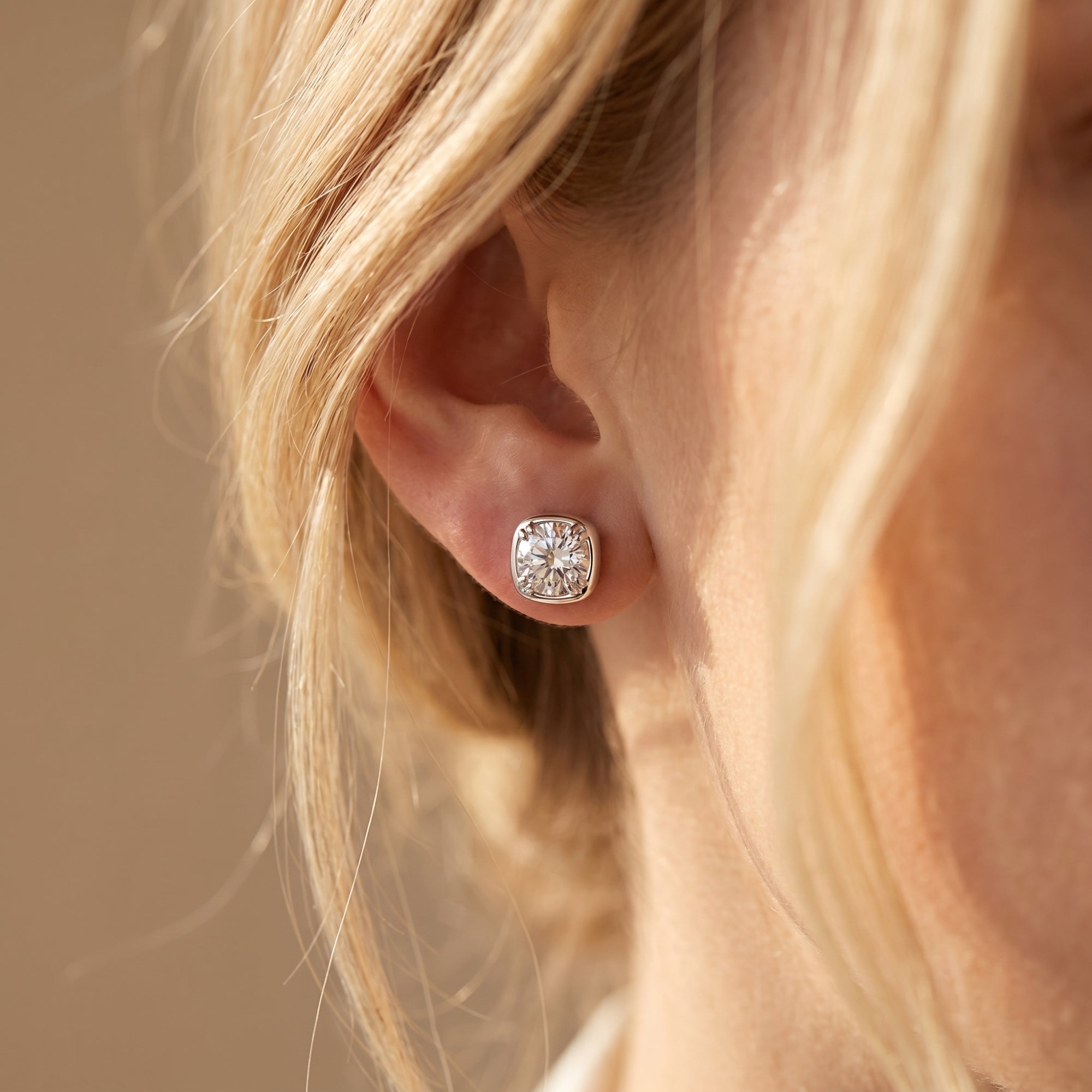 Silver Gabriella cushion-halo moissanite stud earring worn on a woman's ear.