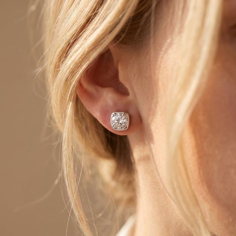 Silver Gabriella cushion-halo moissanite stud earring worn on a woman's ear.