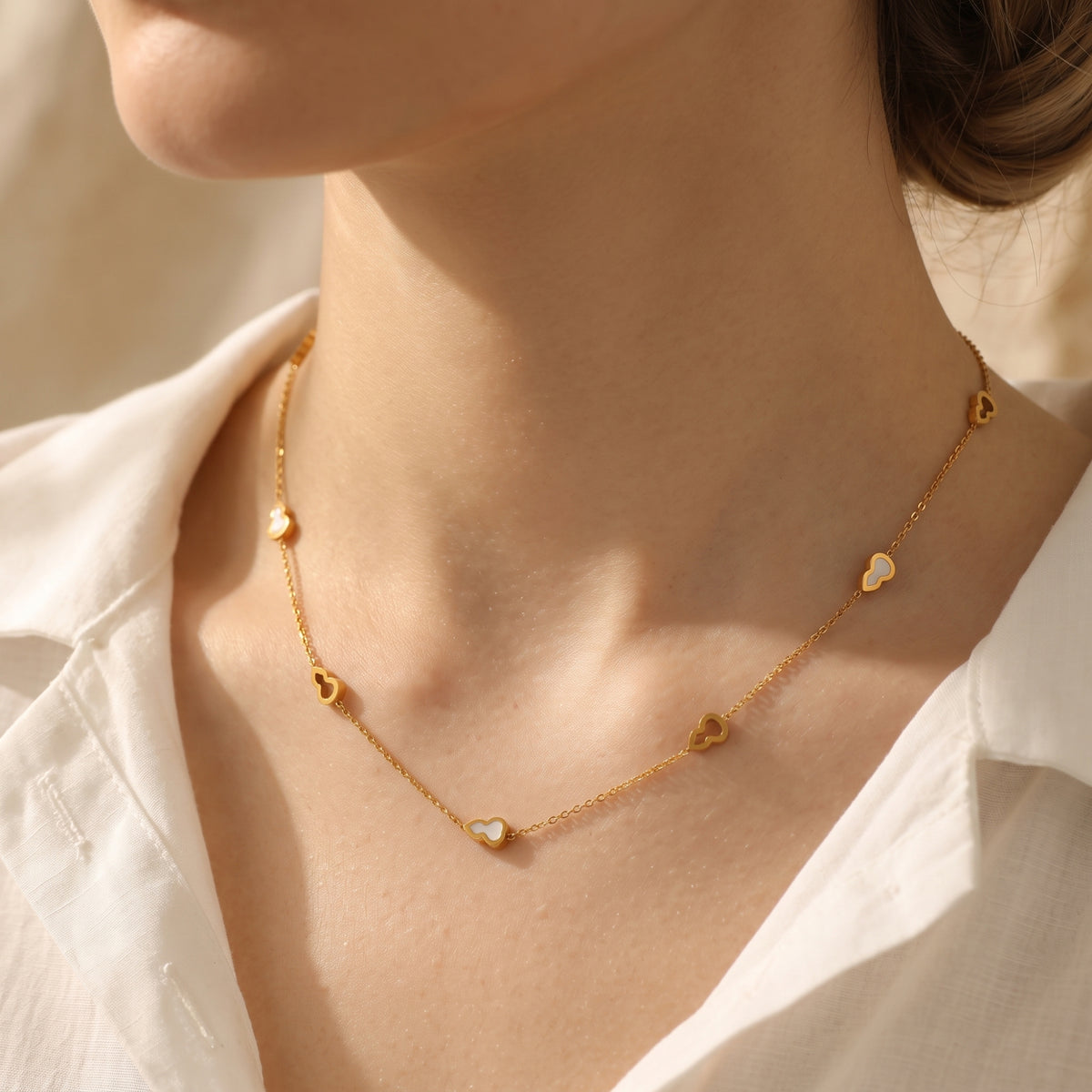 Close-up of a model wearing the gold-tone station necklace with white inlay gourd motifs around the neck.