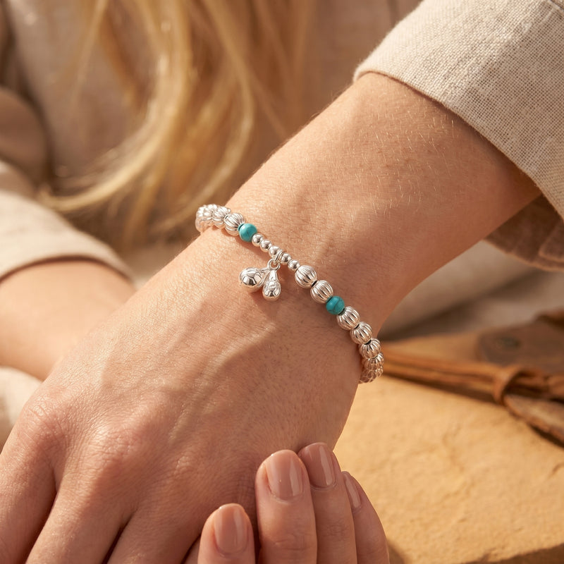 Rio turquoise bracelet in sterling silver worn on a wrist, showing fluted beads and charm.