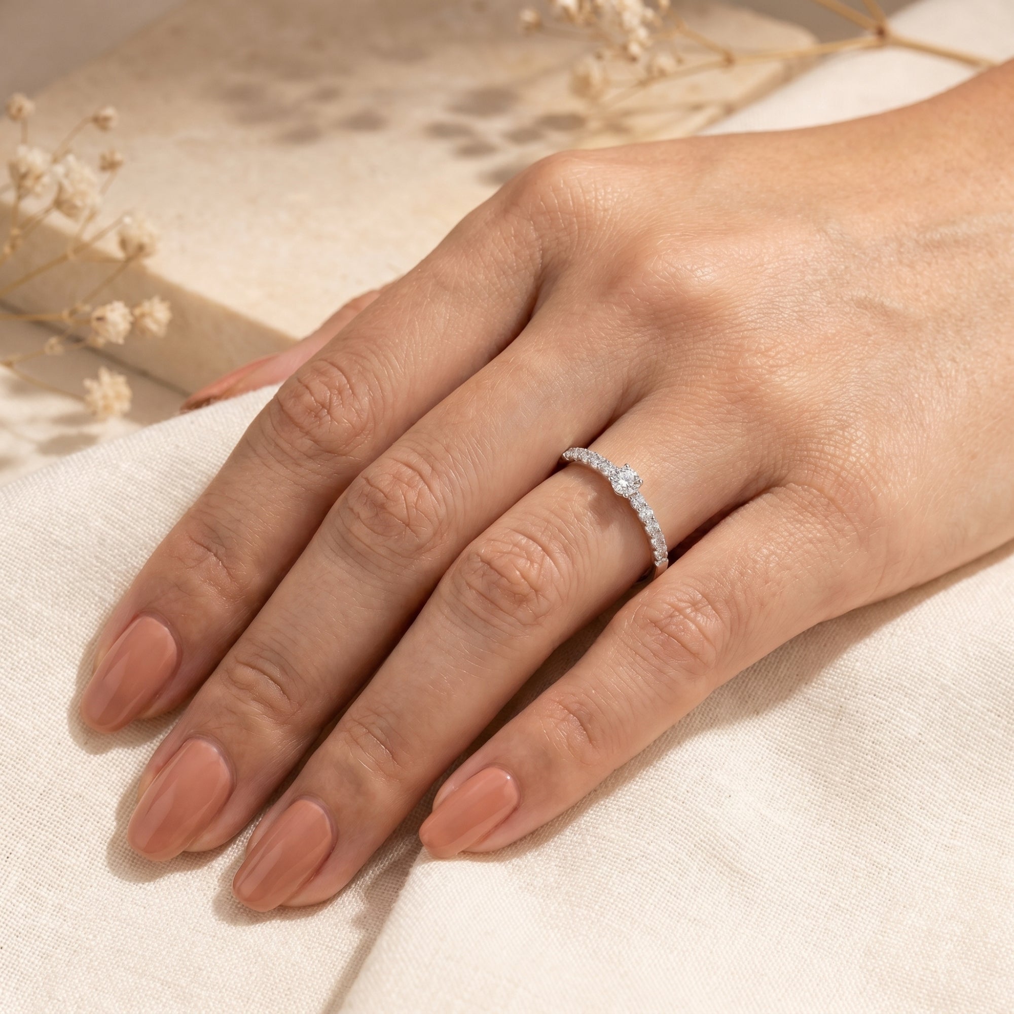 S925 sterling silver moissanite engagement ring on a model's hand with soft fabric.