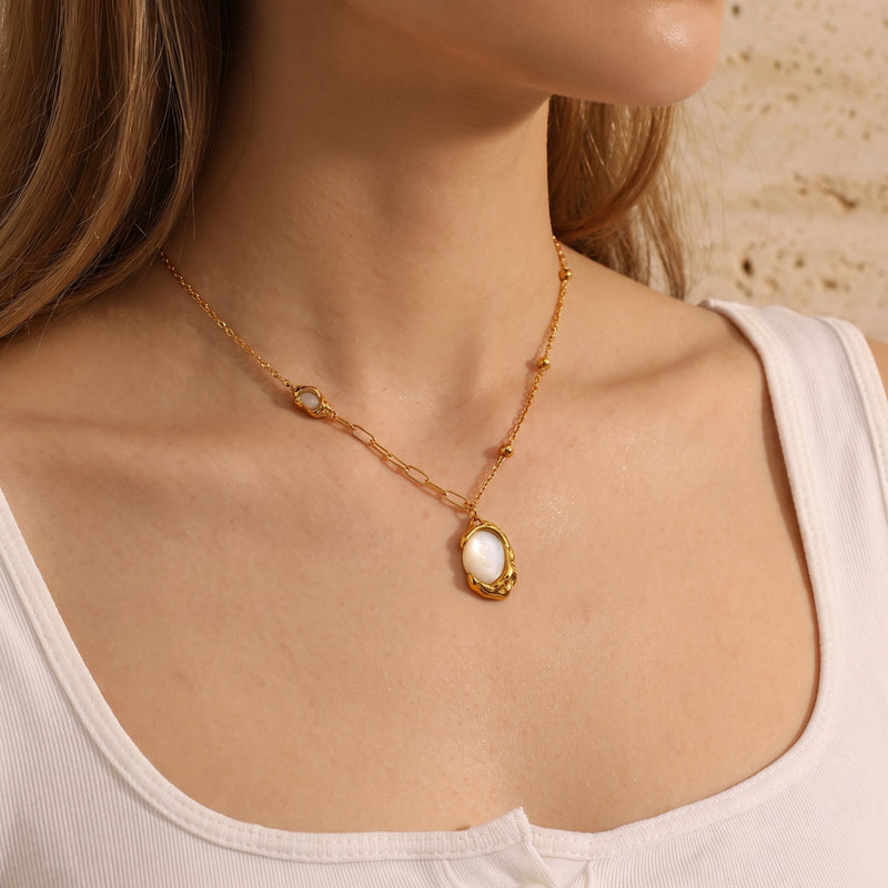 Side view of a model wearing the gold-tone molten oval mother-of-pearl pendant necklace.