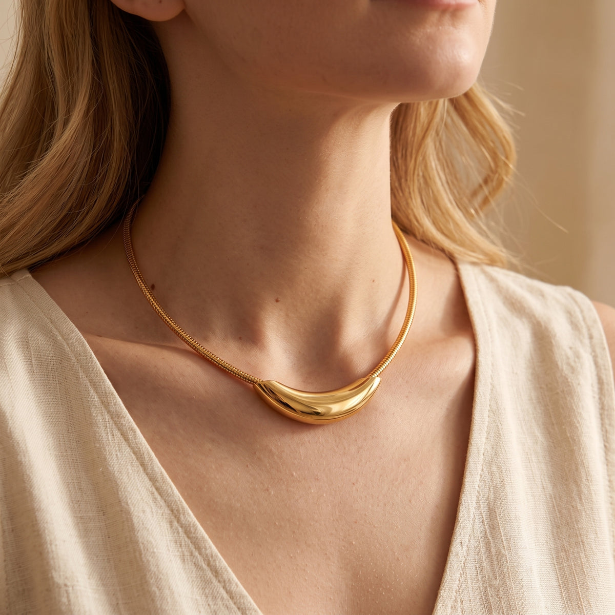 On-model view of the gold-tone curved crescent collar necklace sitting along the collarbone.