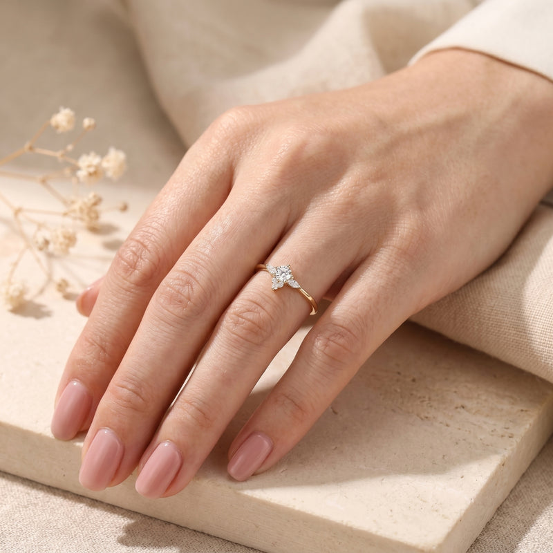 Yellow gold Lysianna ring with a simulated diamond floral cluster worn on a woman's finger.