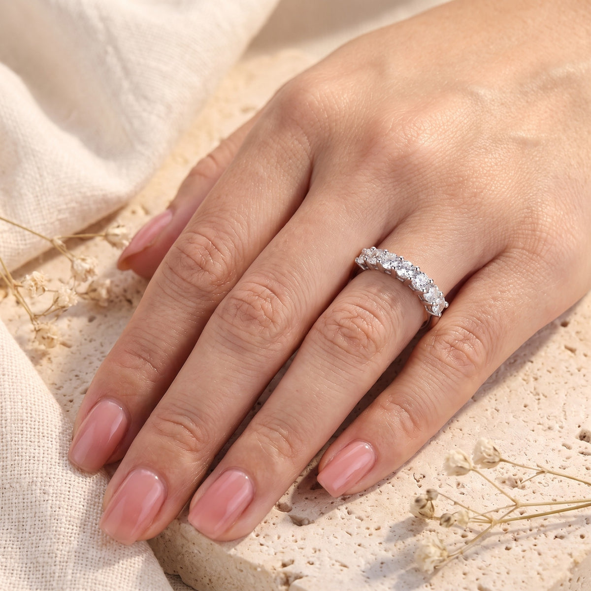 High-angle view of the silver seven-stone band ring worn on a ring finger.