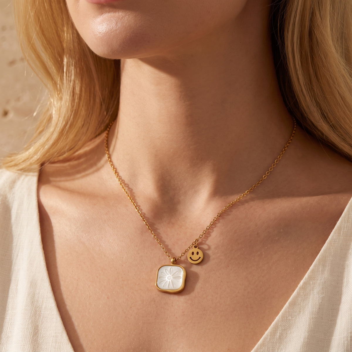 Model wearing the gold-tone daisy shell pendant necklace with a smiley-face charm at the neckline.
