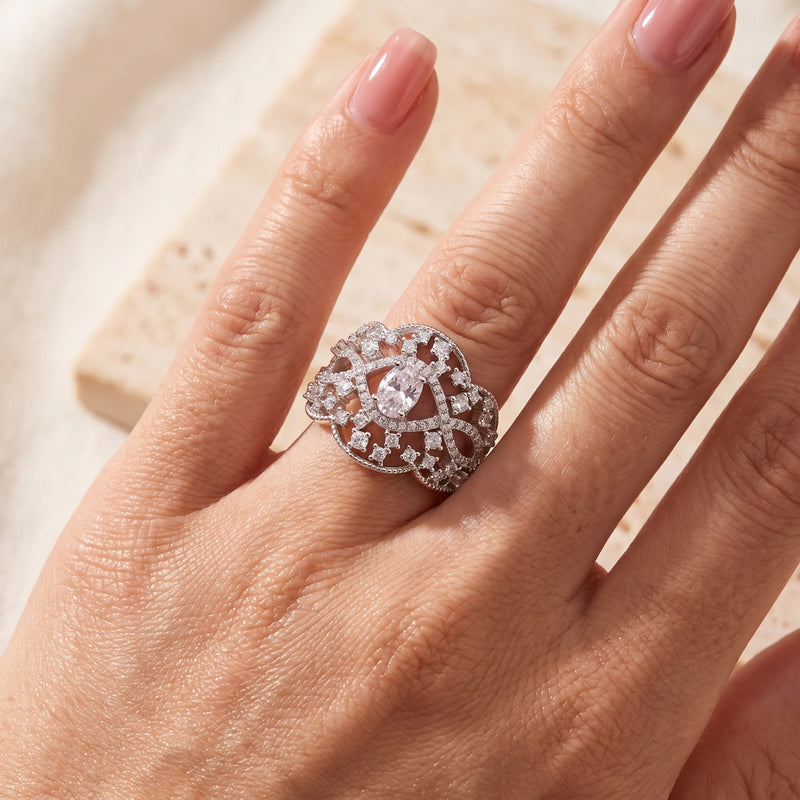 Silver openwork lace ring with an oval center stone, shown worn on a finger.