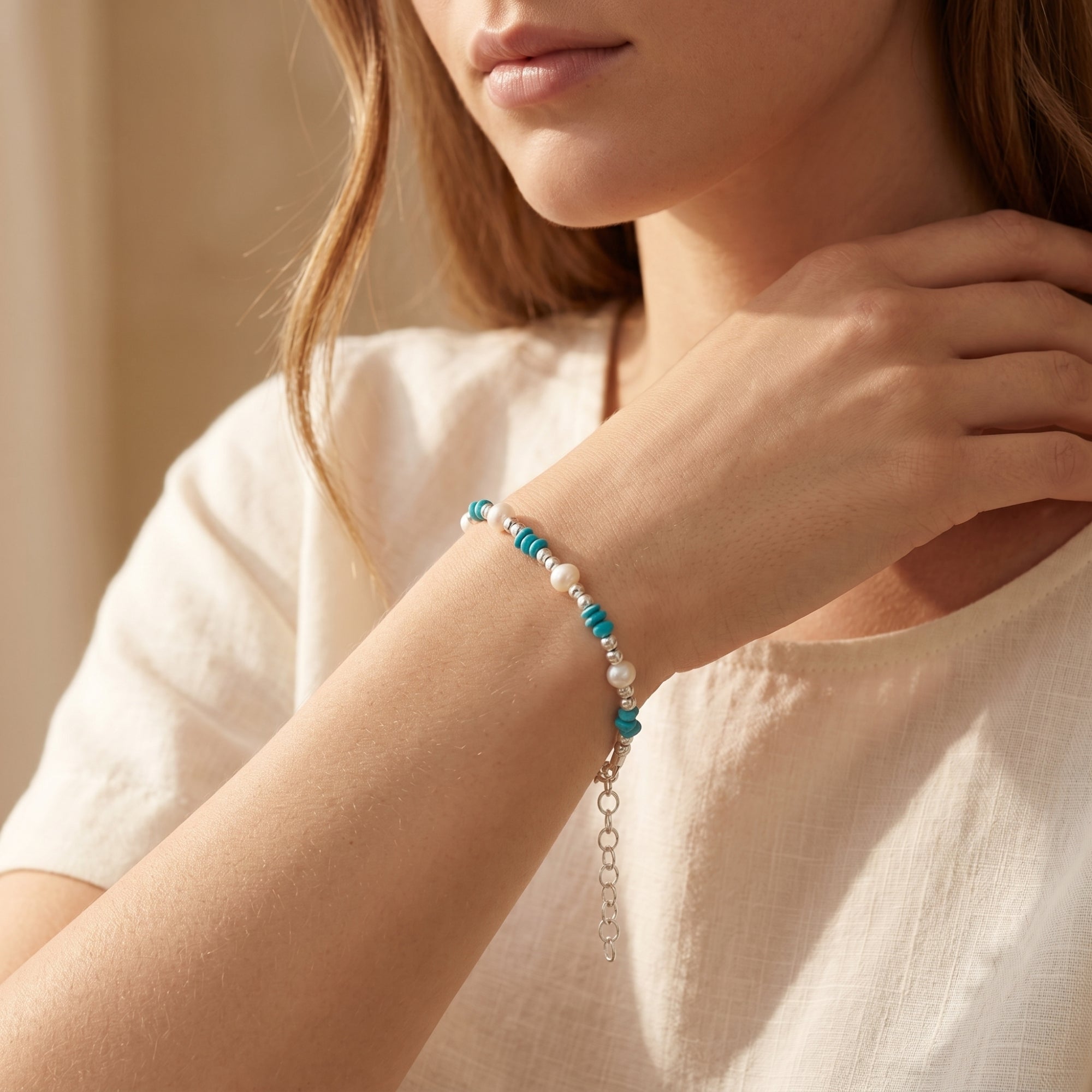 Silver turquoise and pearl bead bracelet worn on a model's wrist.