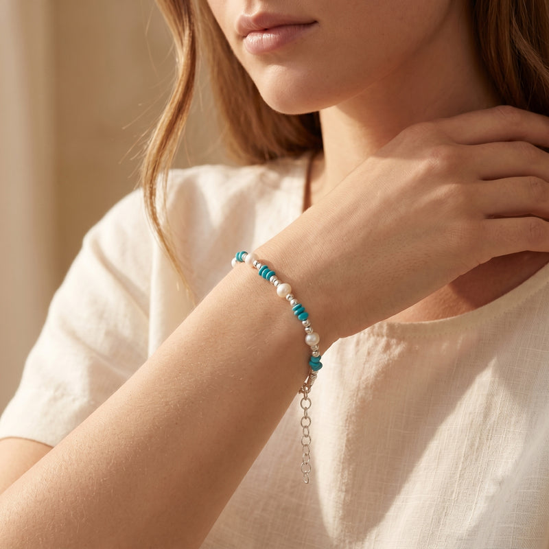 Silver turquoise and pearl bead bracelet worn on a model's wrist.