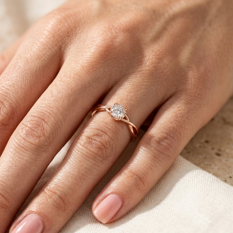 Rose gold promise ring with a round cut moissanite worn on a woman's finger.